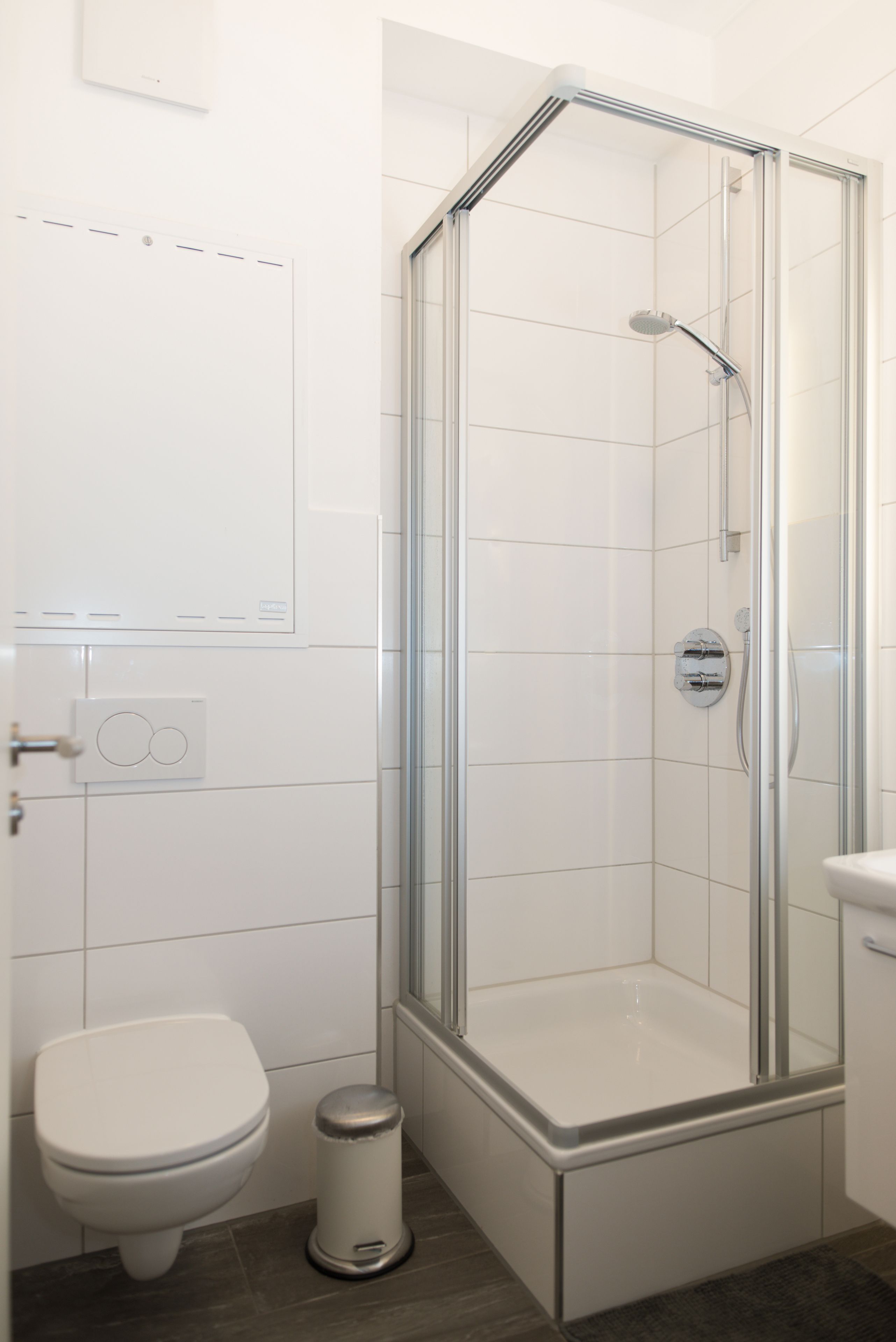 A modern bathroom with a glass-enclosed shower, a toilet, and a sink.