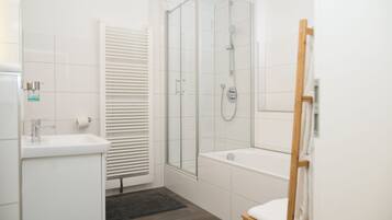 Une salle de bain moderne avec une douche à parois de verre, une baignoire sur pied et un lavabo blanc.