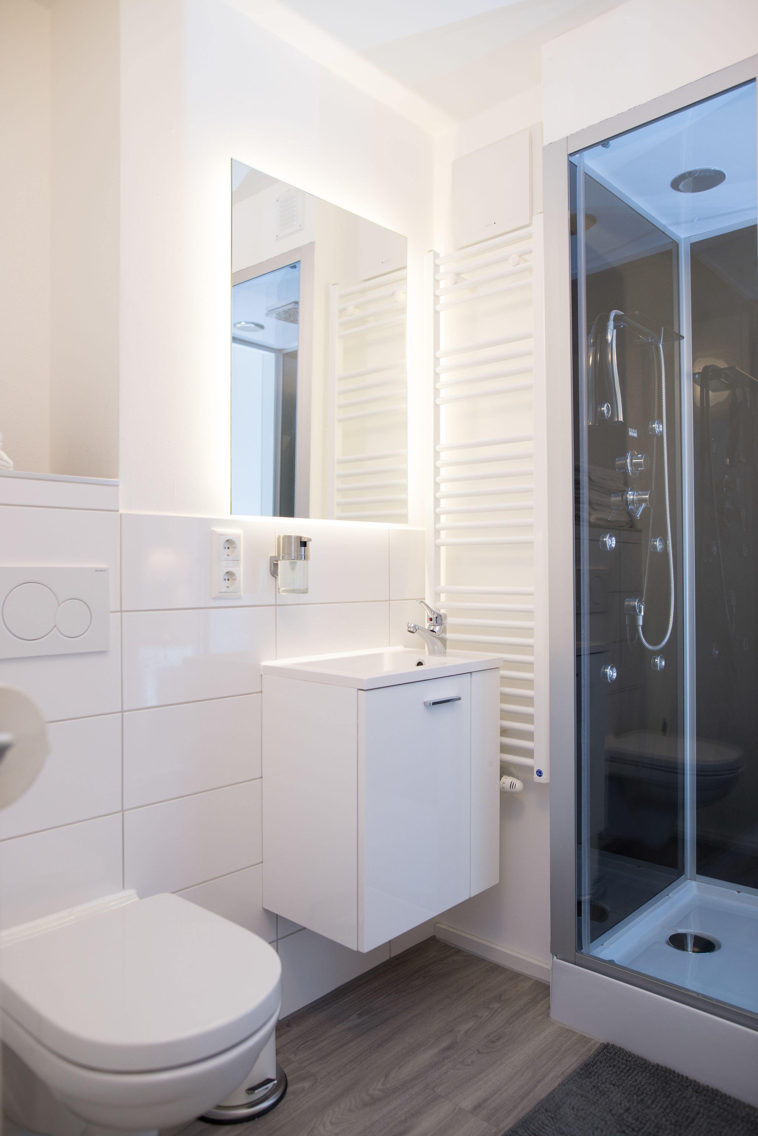A modern bathroom with a toilet, a sink, a mirror, and a glass-enclosed shower.