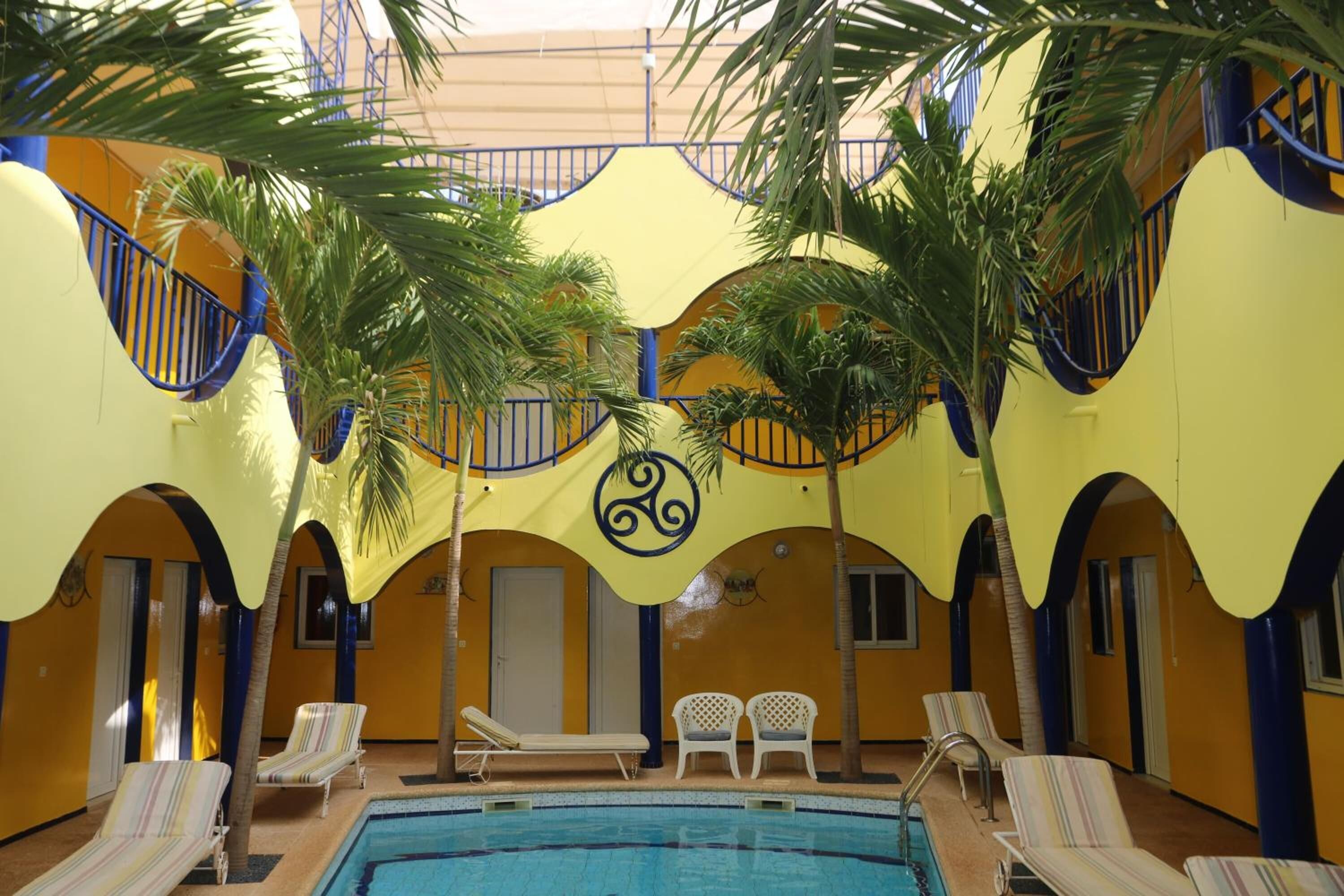 Una piscina interior con sillones de descanso y palmeras.