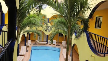 A pool area with lounge chairs, palm trees, and a yellow and blue color scheme.