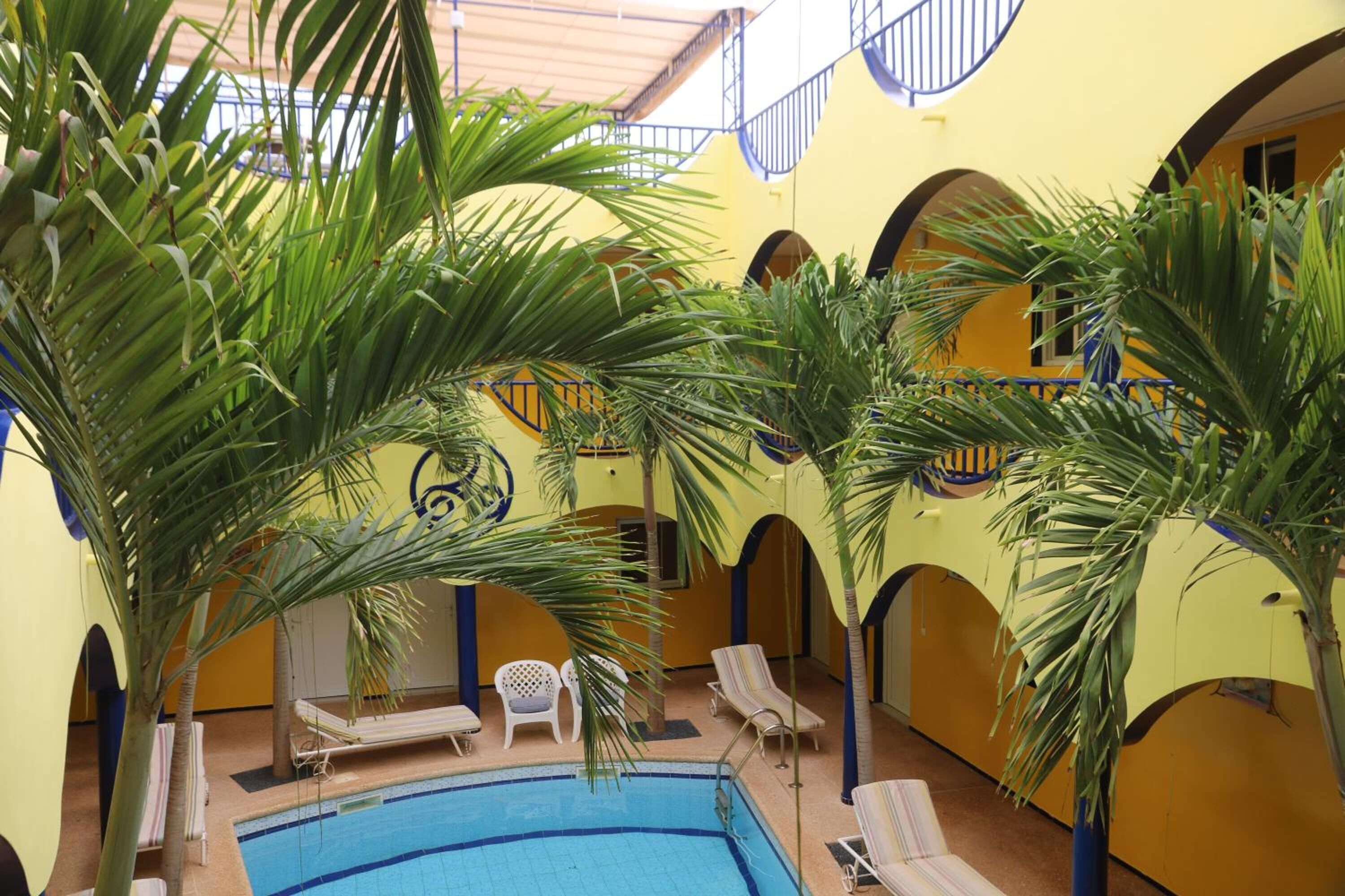 An indoor swimming pool with lounge chairs and palm trees.