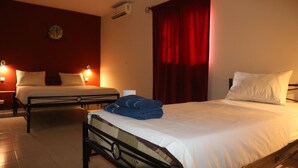 Habitación de hotel con dos camas, una cortina roja e iluminación empotrada.