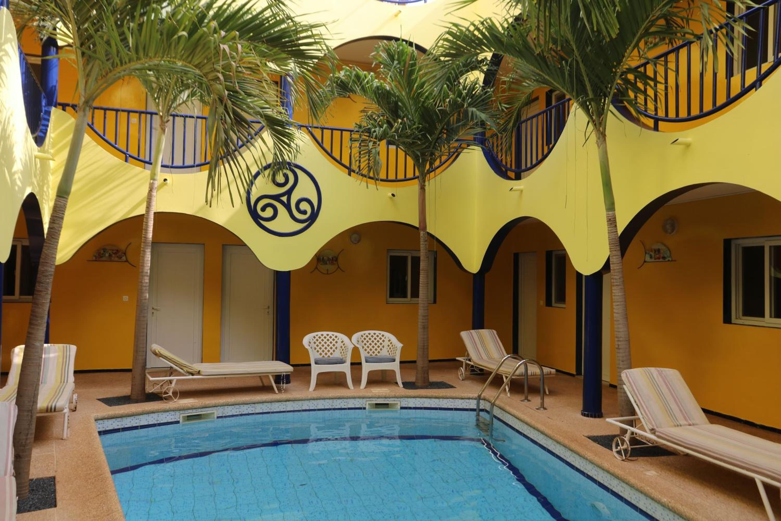 An indoor swimming pool with lounge chairs and palm trees.