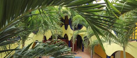 An indoor pool area with palm trees and lounge chairs.