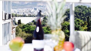 A balcony with a table featuring fruits and a bottle, overlooking a cityscape. - A Diamont with amazing view (Athens)