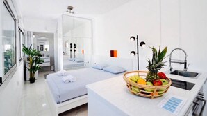 A modern hotel room with a bed, a small kitchenette, a mirror, and a fruit basket. - A Diamont with amazing view (Athens)