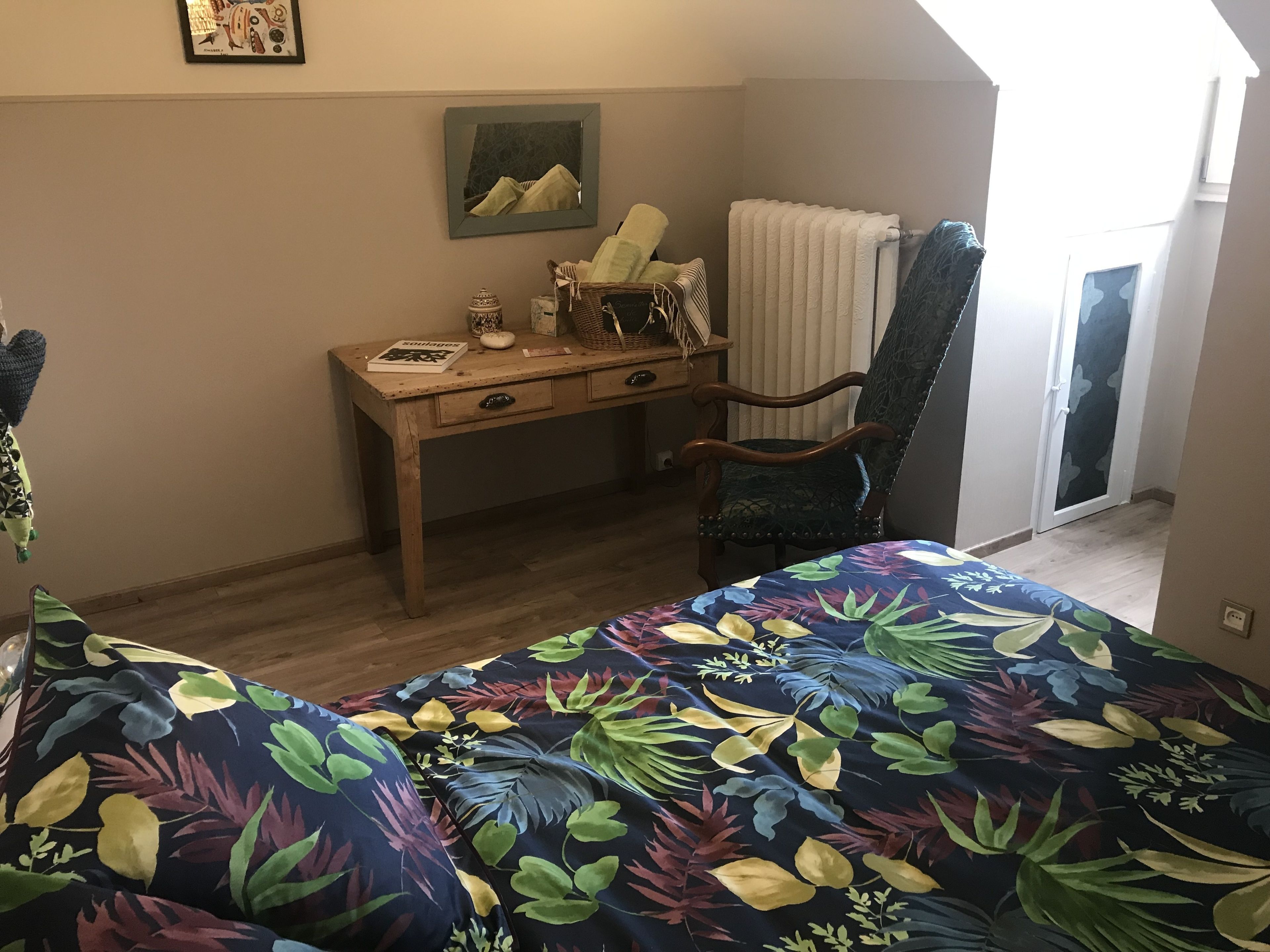 A bedroom with a bed, a desk, a chair, a radiator, and a window.