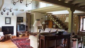 A spacious living area with a fireplace, a sofa, a coffee table, and a staircase leading to an upper level.