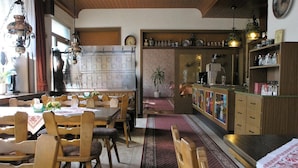 Un restaurant chaleureux avec des tables et des chaises en bois, un coin bar avec des étagères et un mur décoratif.