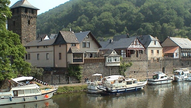 Une ville riveraine, avec des bâtiments historiques et des bateaux amarrés le long du quai.