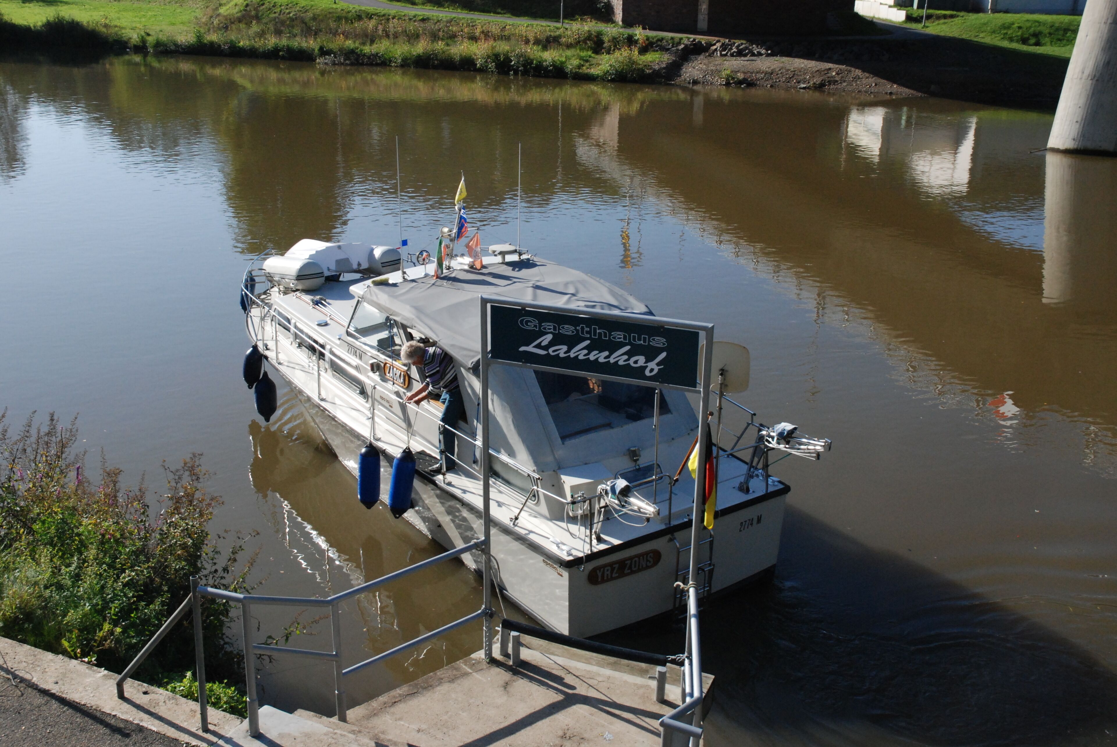 A boat docked at a pier with a sign reading "Gasthaus Lahulhof."