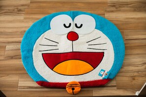 Een pluchen speeltje, lijkend op een cartoonfiguur, met een rode neus en gesloten ogen, op een houten vloer.