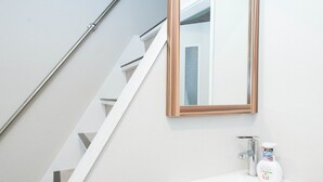 Une salle de bain moderne avec un lavabo blanc, un meuble en bois et un miroir au-dessus du lavabo.