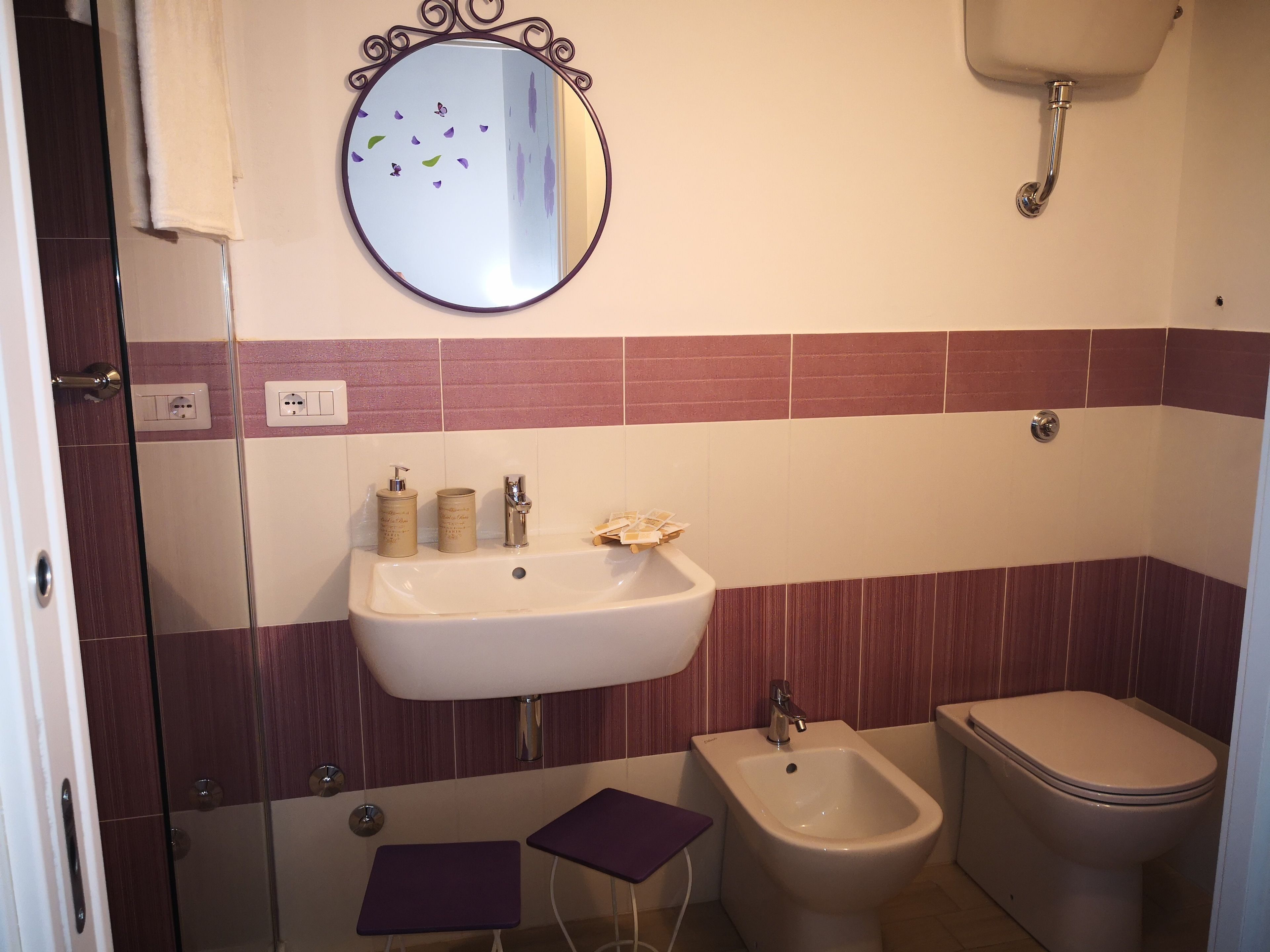 A bathroom with a sink, bidet, toilet, and a mirror with decorative elements.