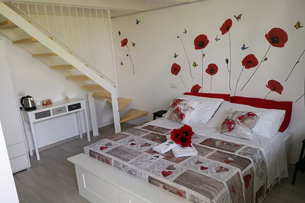 A bedroom with a bed, a desk, and a staircase.