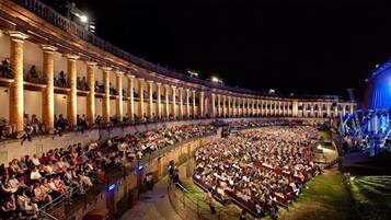 Um grande anfiteatro histórico com assentos em terraços e uma área de palco.