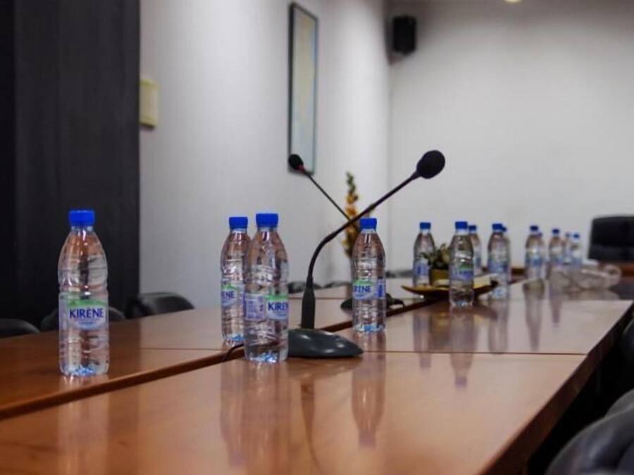 A conference table with water bottles labeled 'KIRENE' and a microphone.