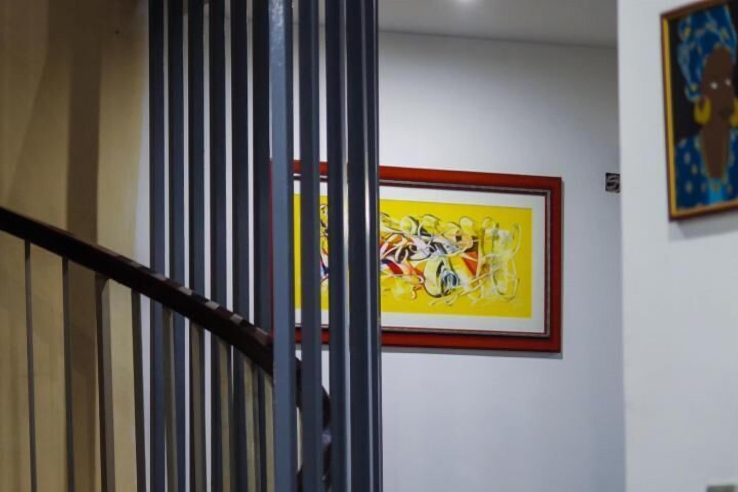 Una scala con ringhiera in metallo, un quadro astratto incorniciato a parete e un'opera d'arte più piccola sopra.
