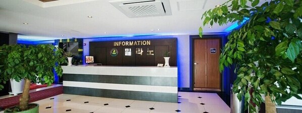 A reception area with a reception desk, a sign reading "INFORMATION", and potted plants. - Jeju Milano Hotel (Seogwipo)