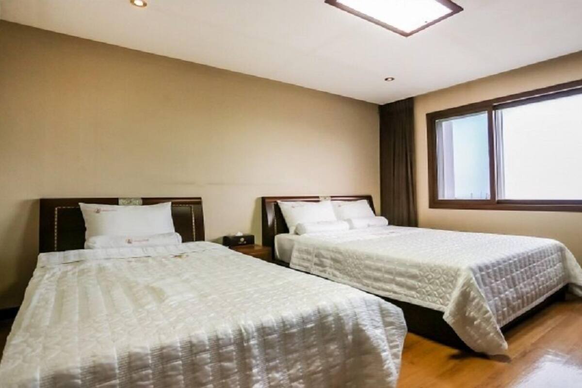 Habitación de hotel con dos camas, un ventanal grande y una lámpara en el techo.