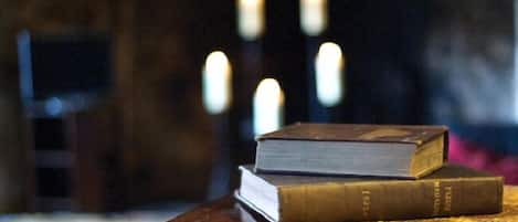 Een stapel boeken op een houten ondergrond met een tafelkleed met patroon.