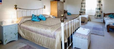 A bedroom with a large bed, a nightstand, a dresser, and a window with curtains.