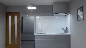 A modern kitchen with grey cabinets, a stainless steel refrigerator, a white countertop, and a pendant light. - YUYU House - Kohama Mei (Osaka)
