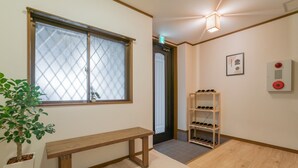 A hallway with a wooden bench, a shoe rack, a potted plant, and a door with a window. - YUYU House - Kohama Mei (Osaka)