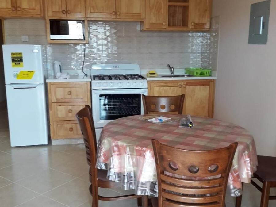 Una cocina con armarios de madera, microondas, estufa y una mesa de comedor con sillas.
