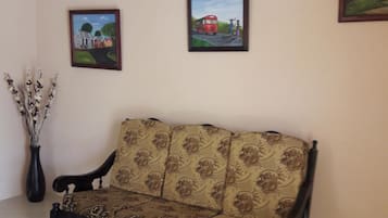 A room with a dark wooden bench, beige walls, and two framed paintings.
