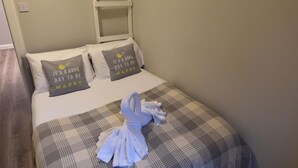 A neatly made bed with a plaid blanket and two pillows, a white ladder against the wall, and a painting of a bridge on the wall. - First - Slateford House Apartment (Edinburgh)
