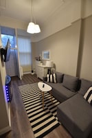 A modern living room with a grey sofa, a black and white striped rug, and a white lamp.