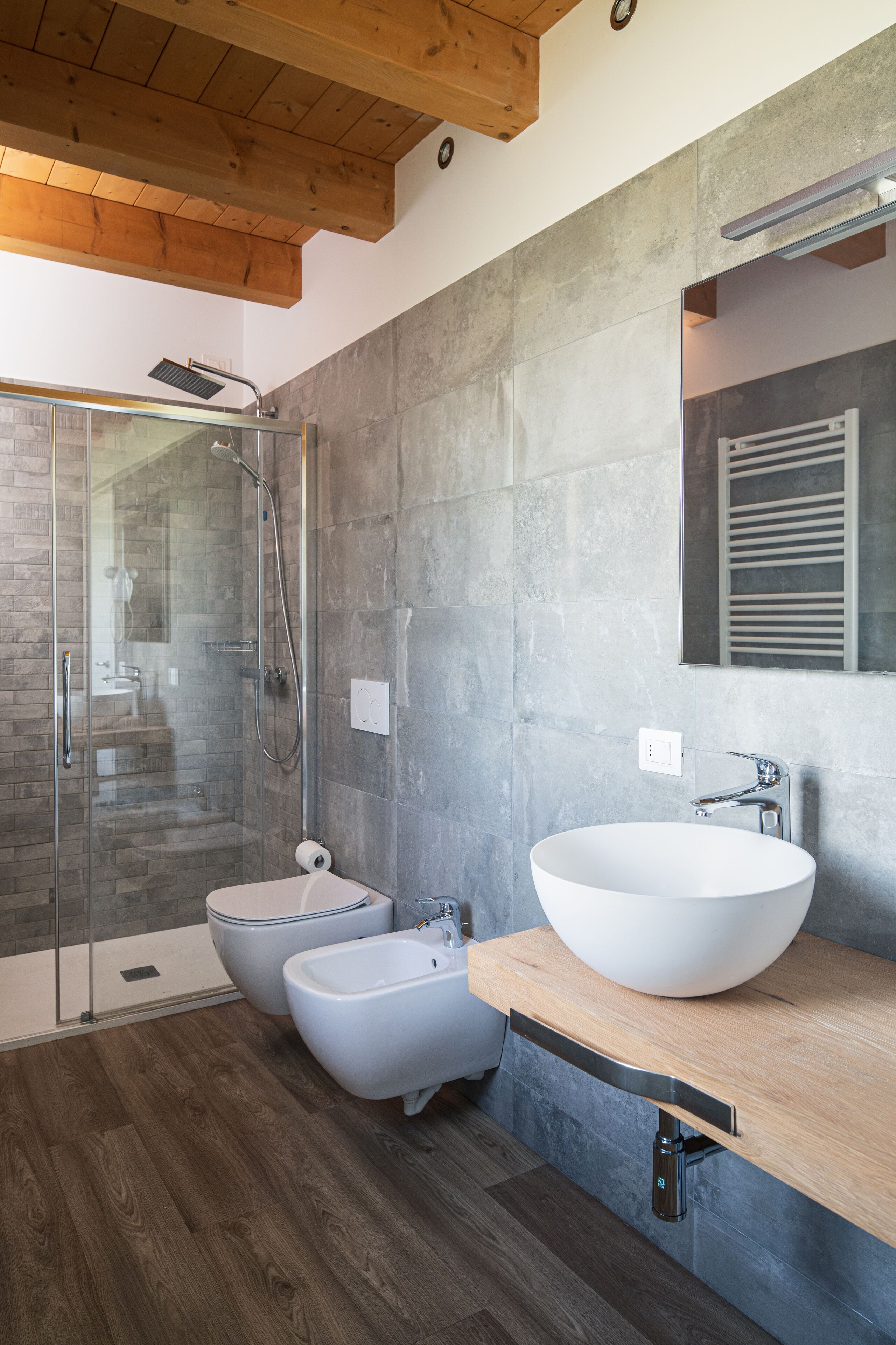 Un baño moderno con ducha de vidrio, un lavamanos grande de color blanco y techo de madera.