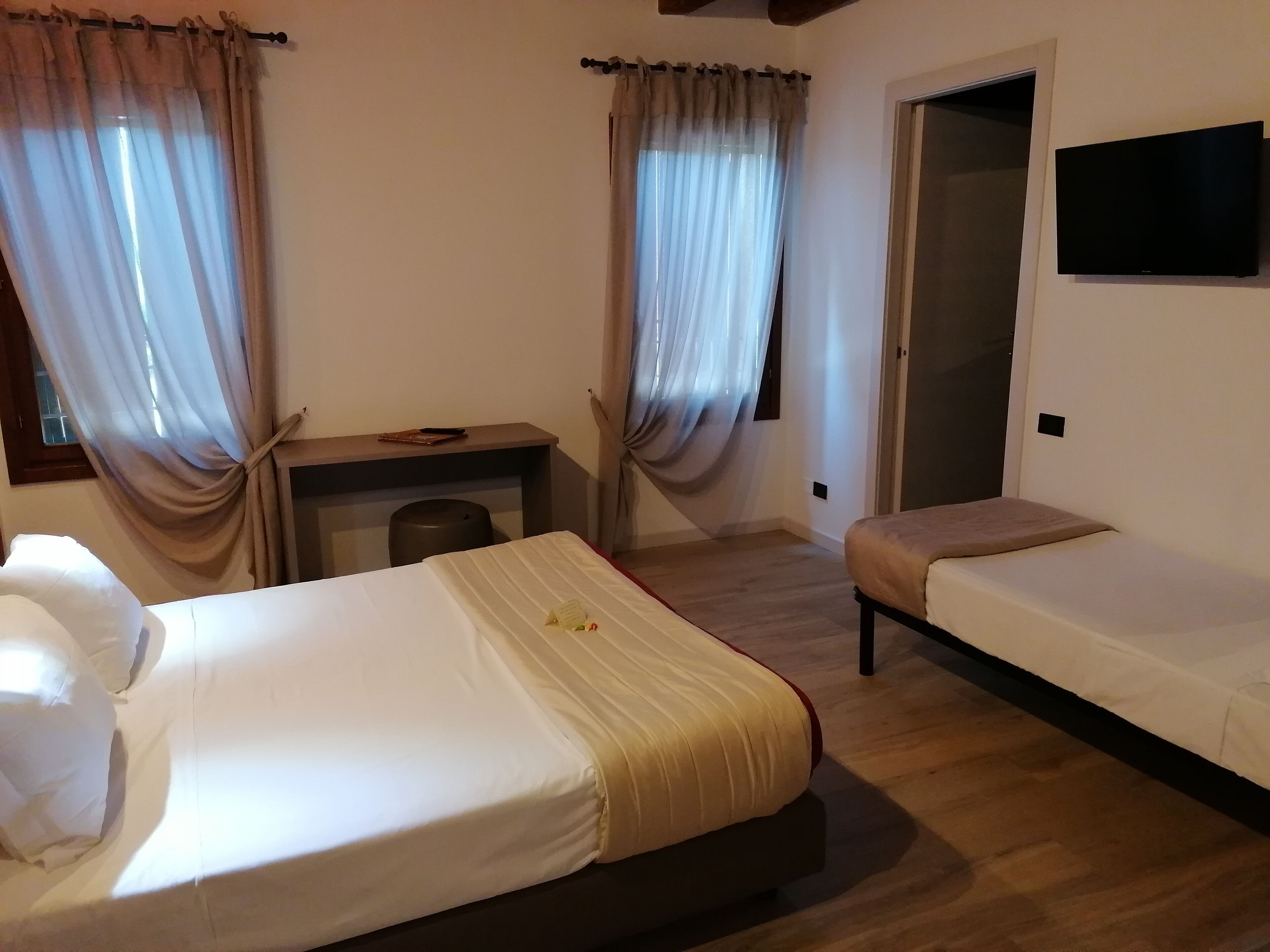 Une chambre d’hôtel avec deux lits, un bureau et une télévision.