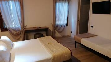 Une chambre d’hôtel avec deux lits, un bureau et une télévision.