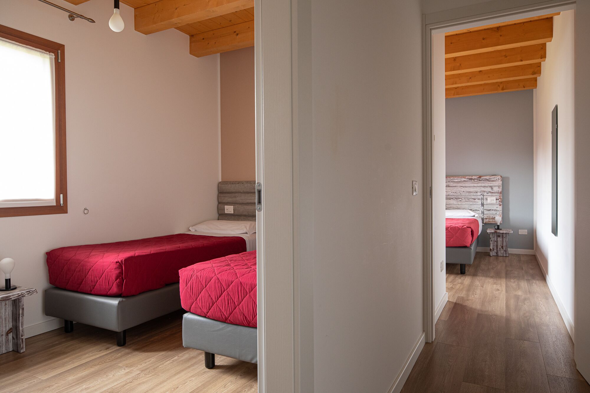 Un dormitorio con dos camas, una mesita de noche, una lámpara y techo de madera.