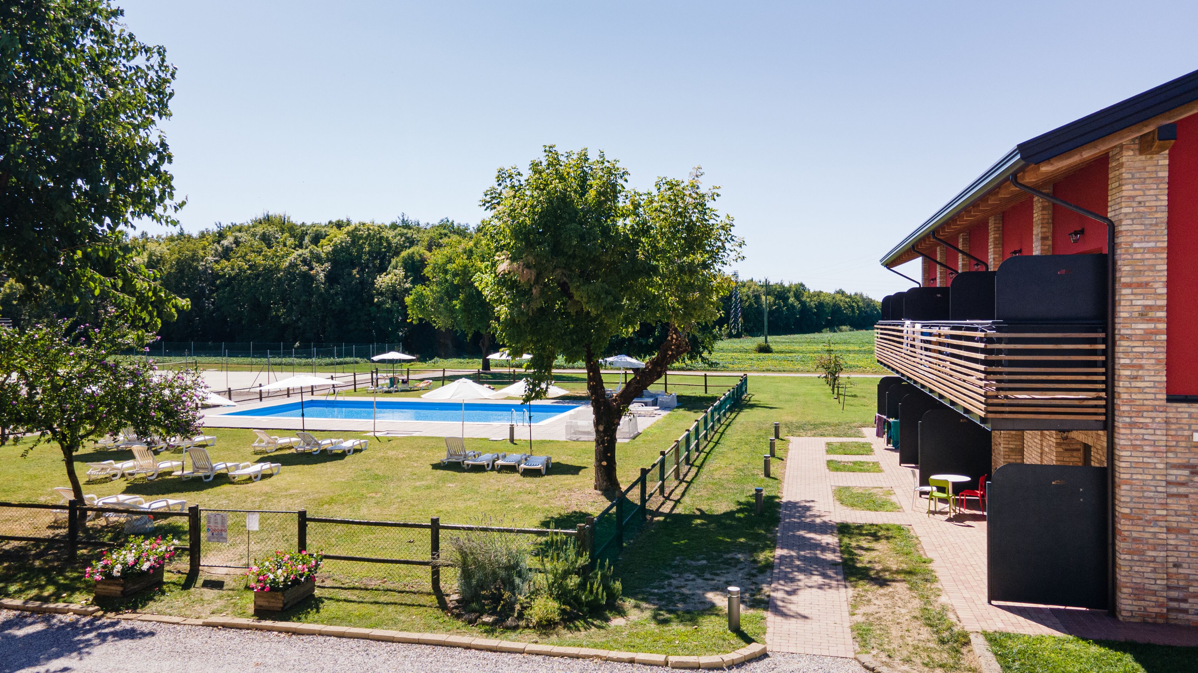A pool area with lounge chairs and a building with a balcony.