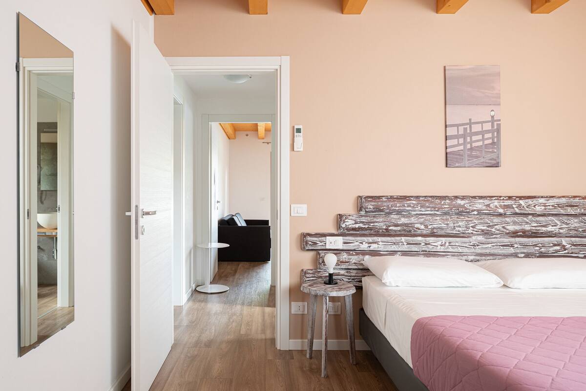 Een slaapkamer met een bed, nachtkastje en een aan de muur hangend kunstwerk.