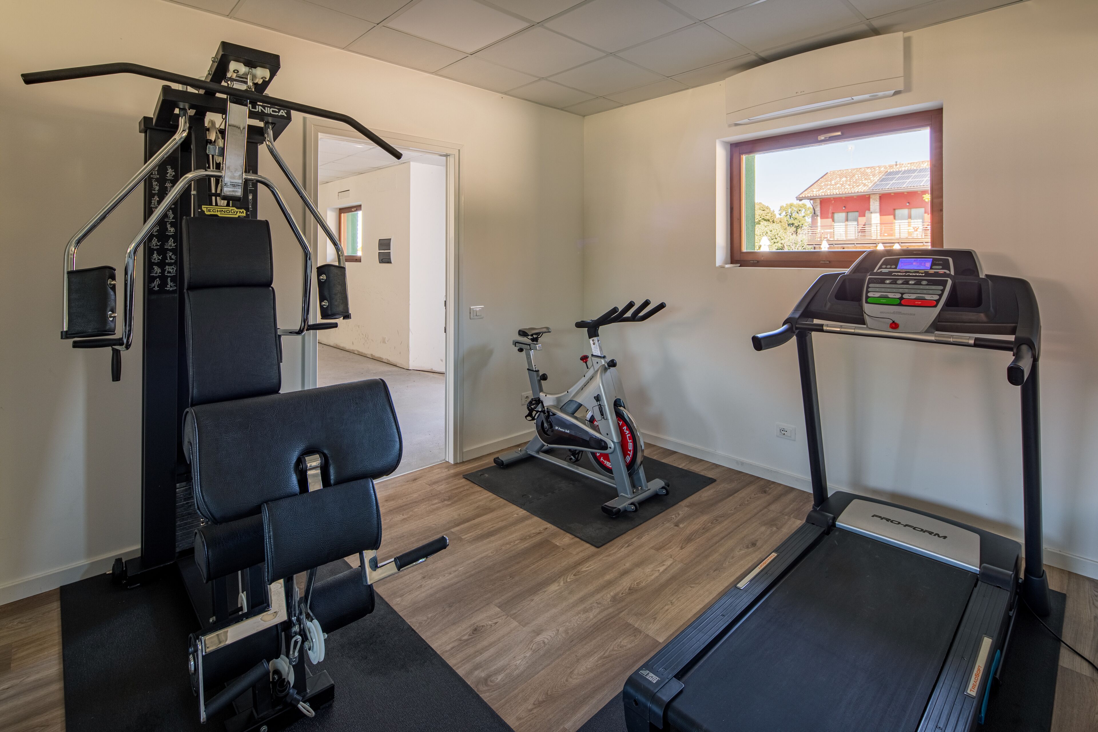 Un gimnasio en casa con cinta de correr, bicicleta estática y banco de pesas.