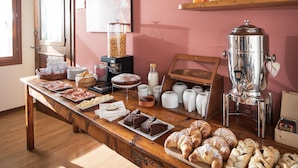 Un buffet de petit-déjeuner comprenant des viennoiseries, du pain et des boissons.