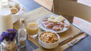 Ein Frühstücksbuffet mit Brot, Käse, Schinken und Müsli auf einem Tisch.