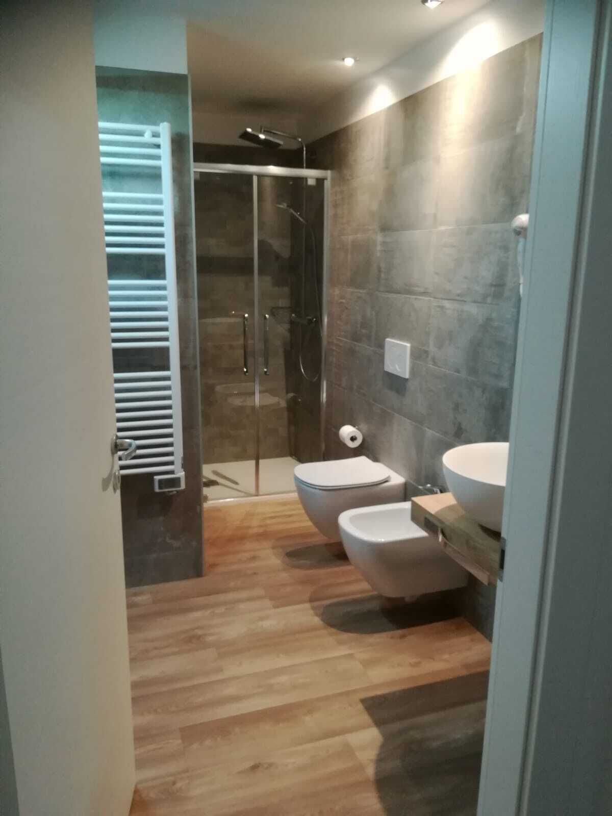 A modern bathroom with a glass shower enclosure, a toilet, and a sink.