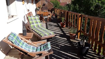 A wooden deck with two lounge chairs, a table, and potted plants.
