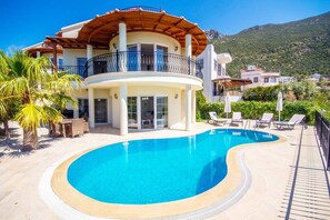 Una piscina al aire libre, sillones reclinables de piscina