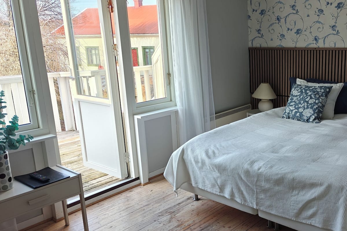 Une chambre à coucher avec un lit, un bureau, une chaise, une fenêtre et une porte.
