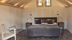 Een slaapkamer met een groot bed, twee nachtkastjes, een stoel en een raam.
