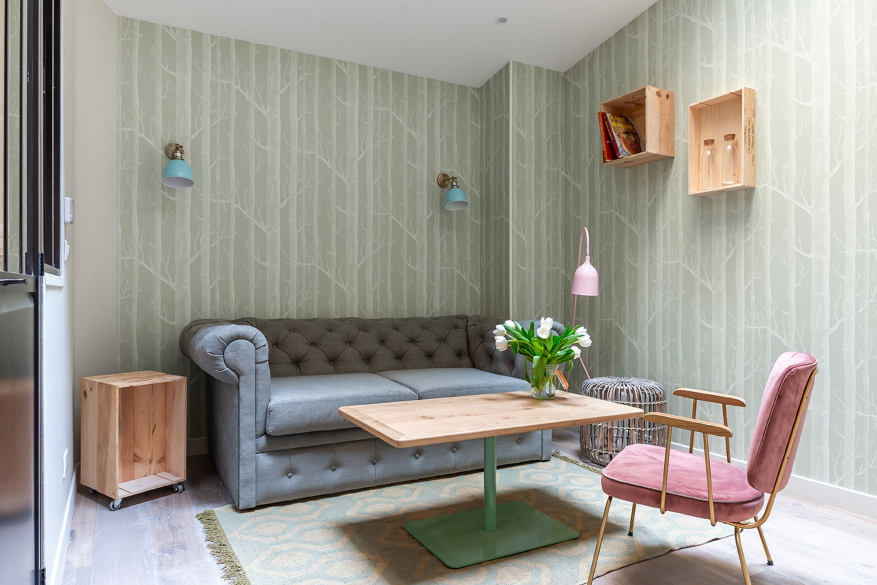 A living room with a grey sofa, a wooden coffee table, a pink chair, and a small side table.