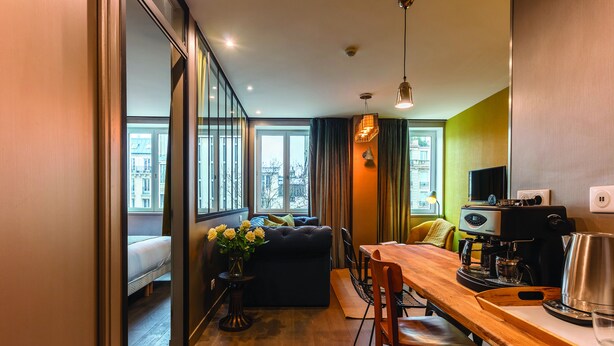 Una sala de estar moderna con sofá, mesa de comedor y cafetera.