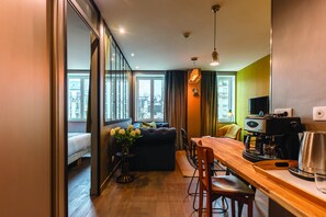 A modern living room with a sofa, a dining table, and a coffee machine. - Be You Luxury Apart'Hotel (Paris)